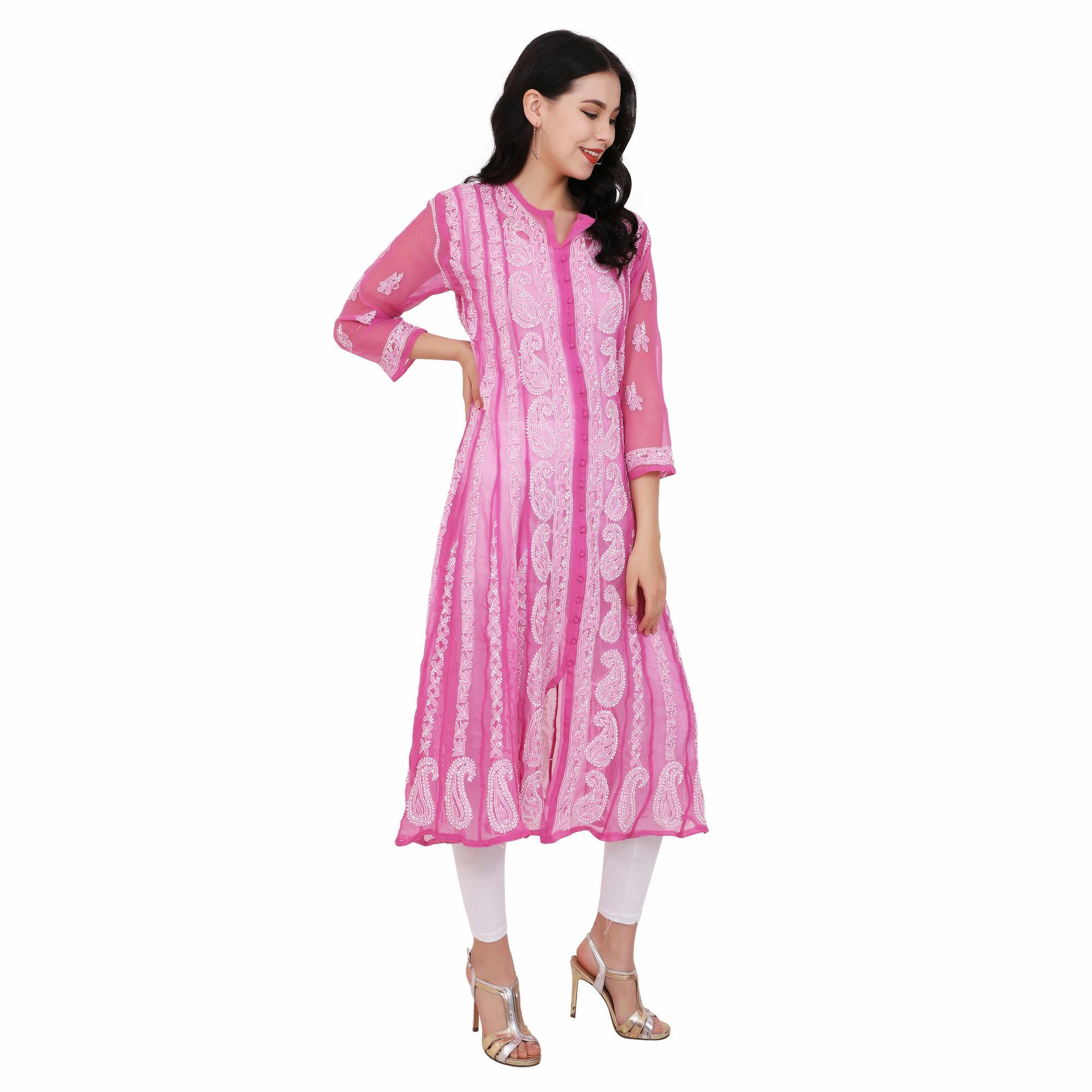 Fashion portrait of a woman in a pink ethnic dress with white accents, set against a white backdrop.
